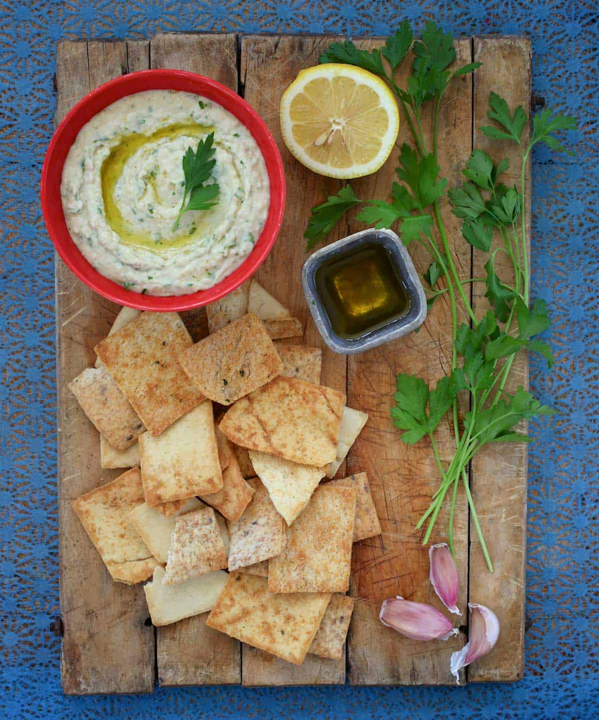 Bowl of Cannellini Bean Dip with Truffle OIl on a wooden board with pita chips