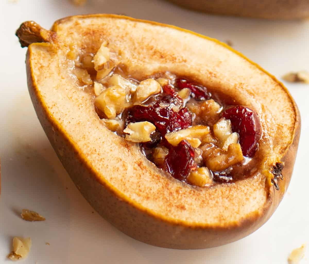 close up shot of a baked half pear stuffed with dried cranberries and chopped walnuts