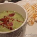 Large white mug filled with a single portion of Zucchini Soup, on a plate next to a panini sandwich.