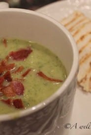 Mug filled with Zucchini Soup, on a plate next to a panini sandwich