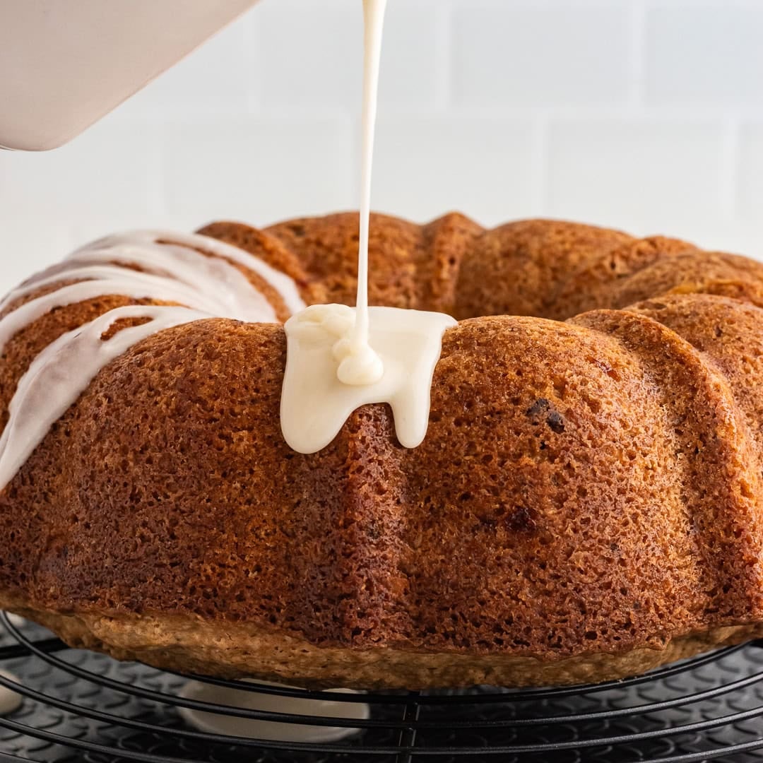 Pouring glaze over the top of the apple bundt cake.