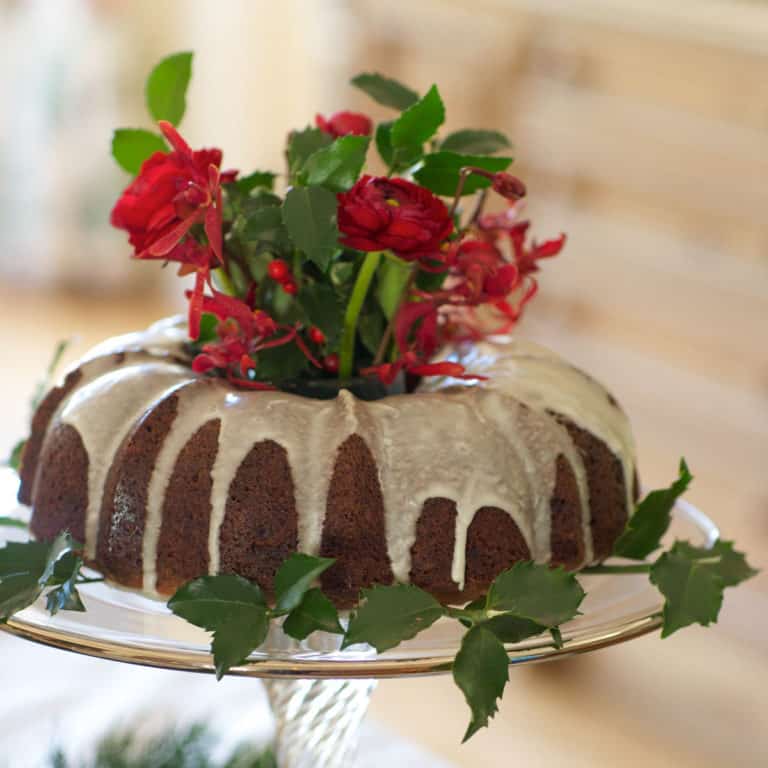 Bundt Apple Cake on a glass cake stand with flowers