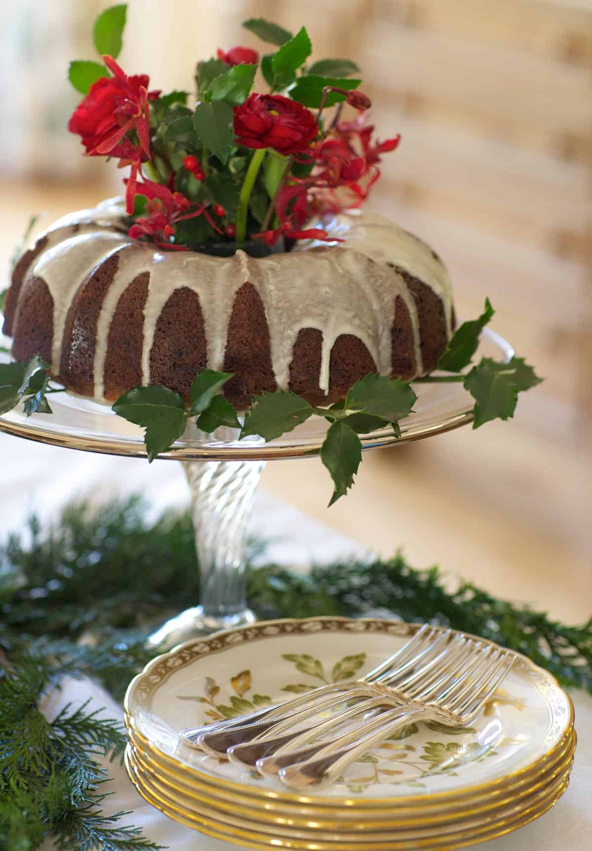 Bundt pan-shaped Apple Cake on a glass cake stand with flowers