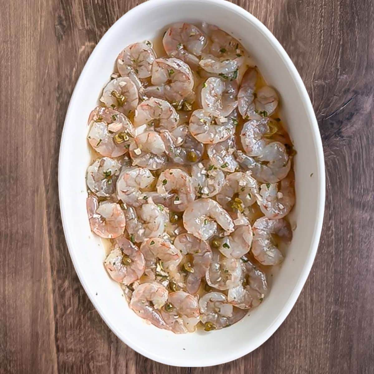 Shrimp added to a white oval baking dish.