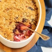 Blackberry Pear Crisp in a white oval dish with a scoop out of one corner