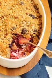 Blackberry Pear Crisp in a white oval dish with a scoop out of one corner