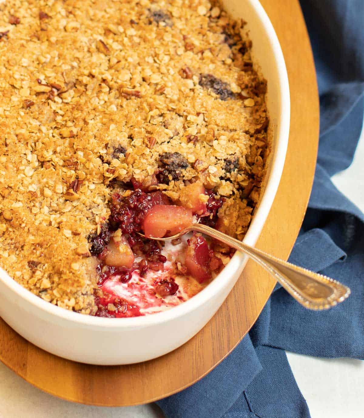 Blackberry Pear Crisp in a white oval dish with a scoop out of one corner