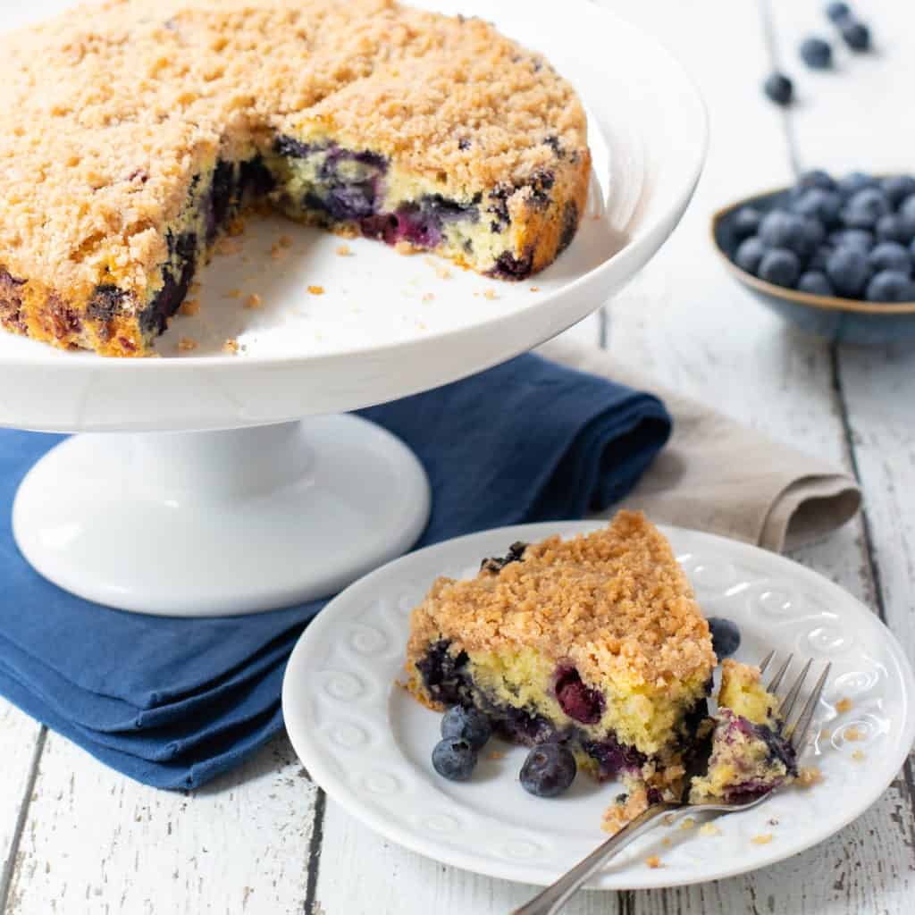 Blueberry Cake on a cake stand with a slice of cake