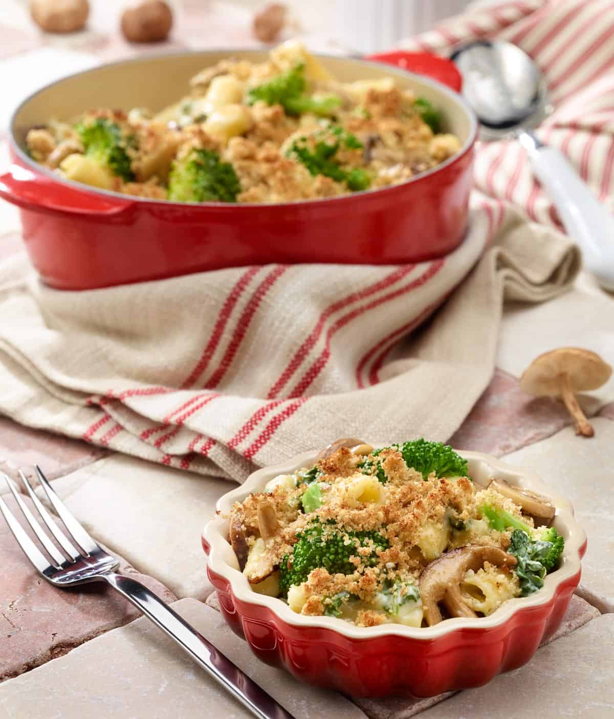 Small dish of broccoli, mushroom, spinach and cheese pasta with larger pan in background