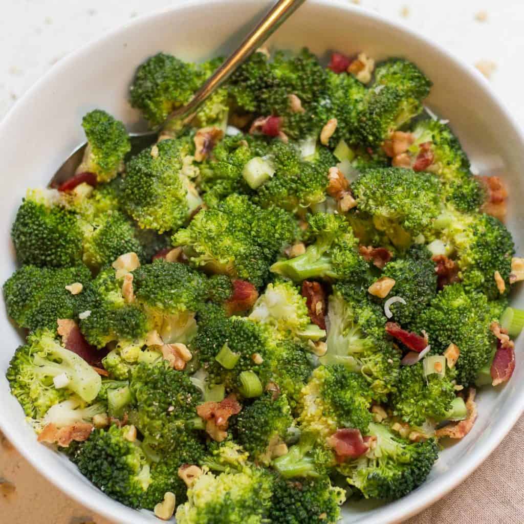 close up of a bowl of broccoli with bacon and walnuts