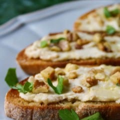 portions of 3 bruschetta topped with bean puree, on a blue plate