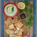 overhead shot of red bowl filled with Cannellini Bean Dip with Truffle Oil, with pita chips alongside