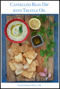 overhead shot of red bowl filled with Cannellini Bean Dip with Truffle Oil, with pita chips alongside