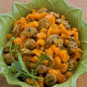 roasted chicken sausage and butternut squash in a green baking dish
