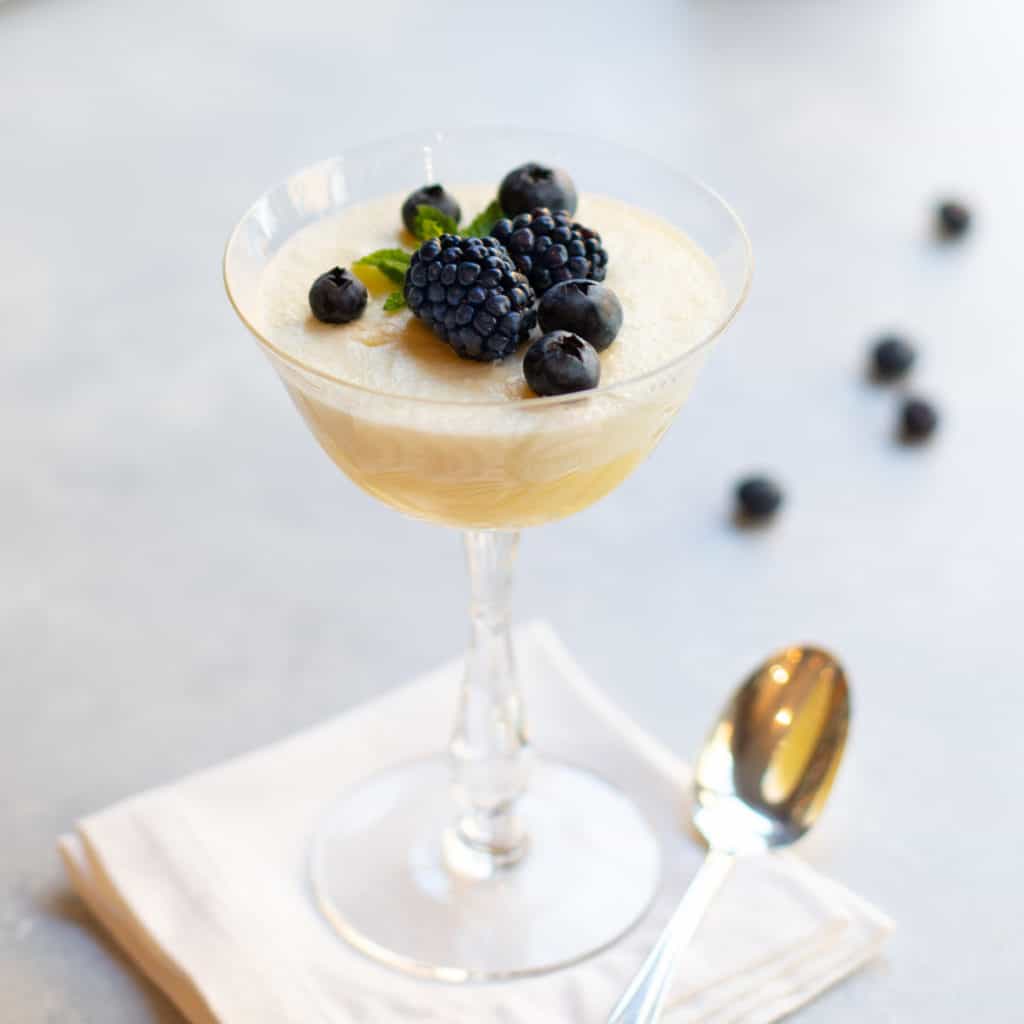 champagne coupe glass filled with Chilled Lemon Souffle and topped with fresh blackberries and blueberries