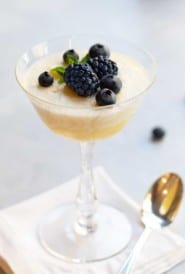champagne coupe glass filled with Chilled Lemon Souffle and topped with fresh blackberries and blueberries.