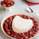 heart shaped coeur a la creme with a spoon inserted in the side, and surrounded by strawberry sauce