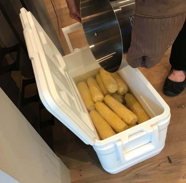 cooler filled with corn and hands pouring in water