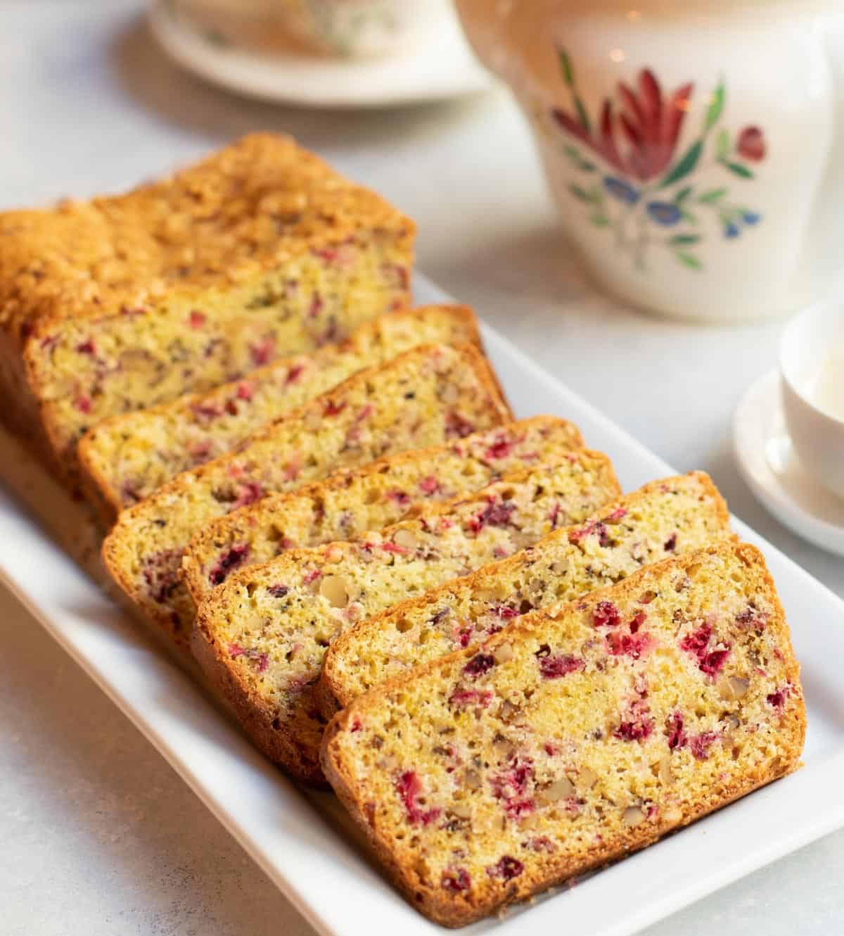 Sliced loaf of Cranberry Nut Bread with a teapot
