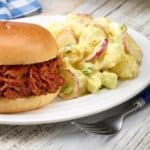 white plate with Dorothy's PotatoPotato Salad shown next to BBQ Beef sandwich