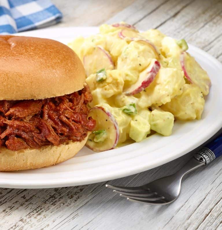 white plate with Dorothy's PotatoPotato Salad shown next to BBQ Beef sandwich