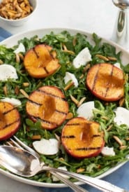 Grilled peach halves and sliced Mozzarella cheese on top of baby arugula salad