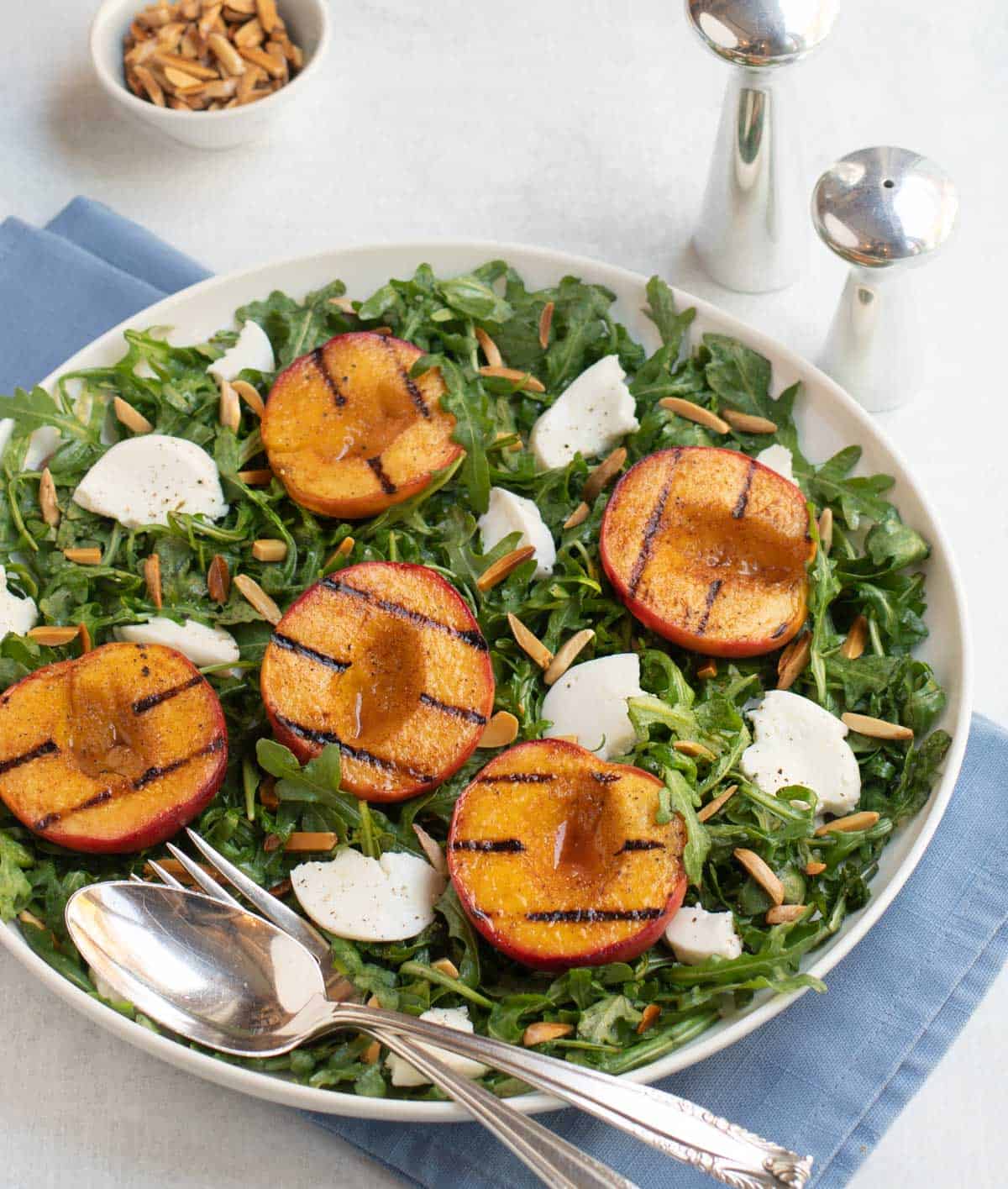 Grilled peaches and sliced burrata cheese atop baby arugula