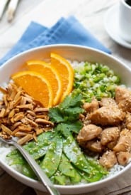 stir fry chicken, pea pods, almonds, green onion and rice arranged in a flat bowl