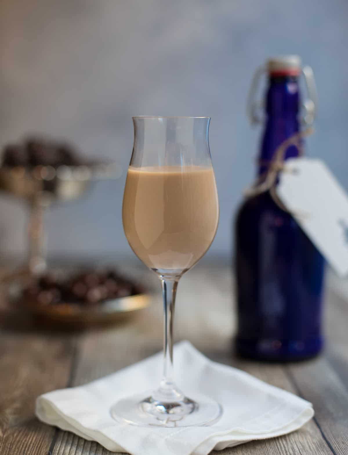 Stemmed glass filled with Irish Cream Liqueur, next to a blue bottle