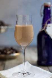 glass holding one serving of Irish Cream Liqueur with a blue bottle in the background
