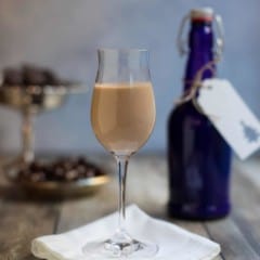 glass holding one serving of Irish Cream Liqueur with a blue bottle in the background