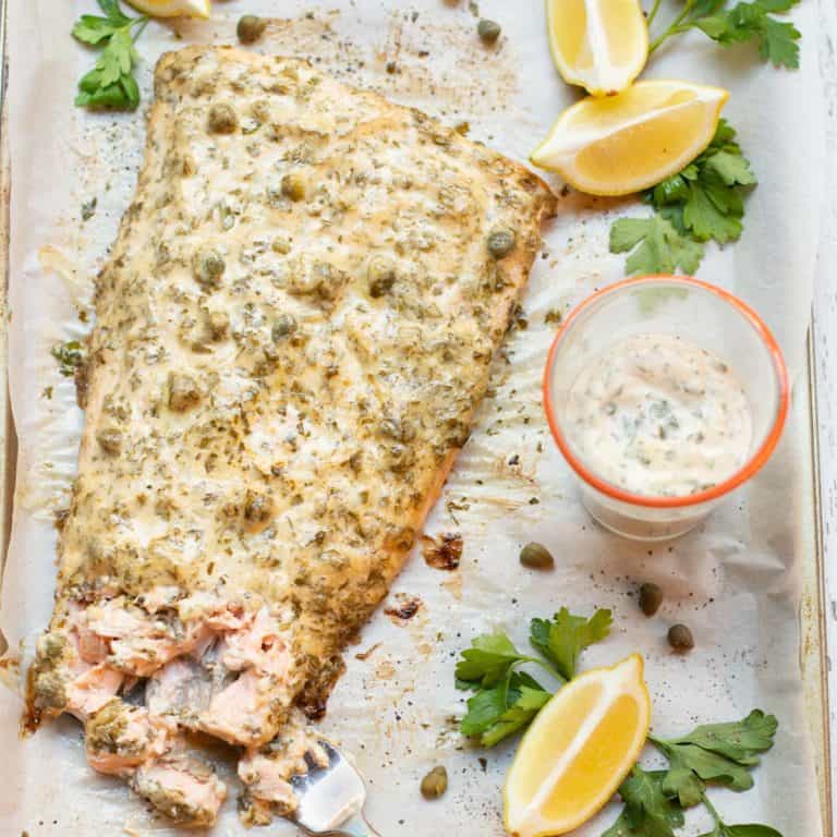 Salmon filet with lemon caper sauce on top and on the side