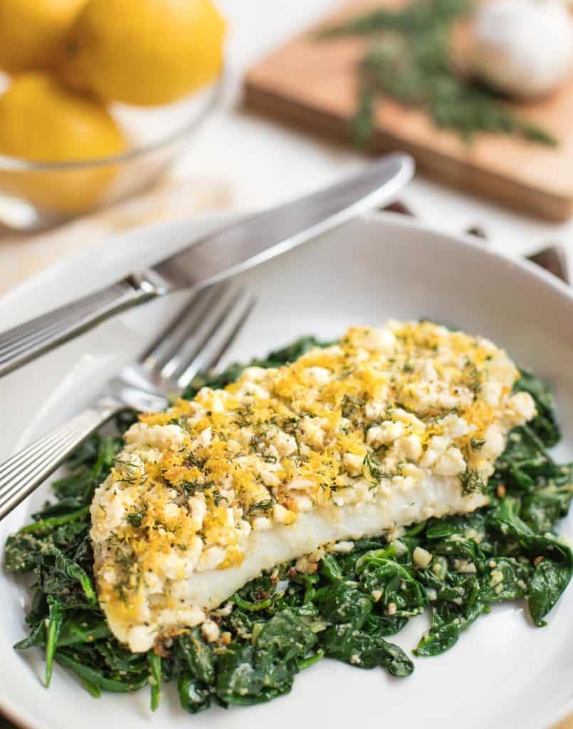 white plate with Roasted Cod on Spinach with Feta,Lemon and Dill