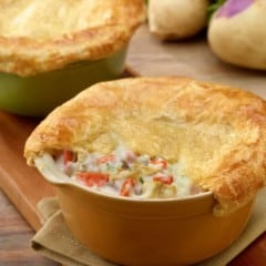 roasted root vegetable pot pie in a tan baking dish, with a corner of the top removed to show the filling