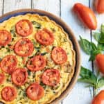 Overhead shot of mushroom, spinach, zucchini pie with sliced tomatoes on top