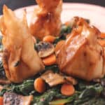 cheese dumplings atop cooked spinach, mushrooms and carrots
