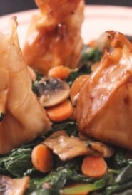 cheese dumplings atop cooked spinach, mushrooms and carrots