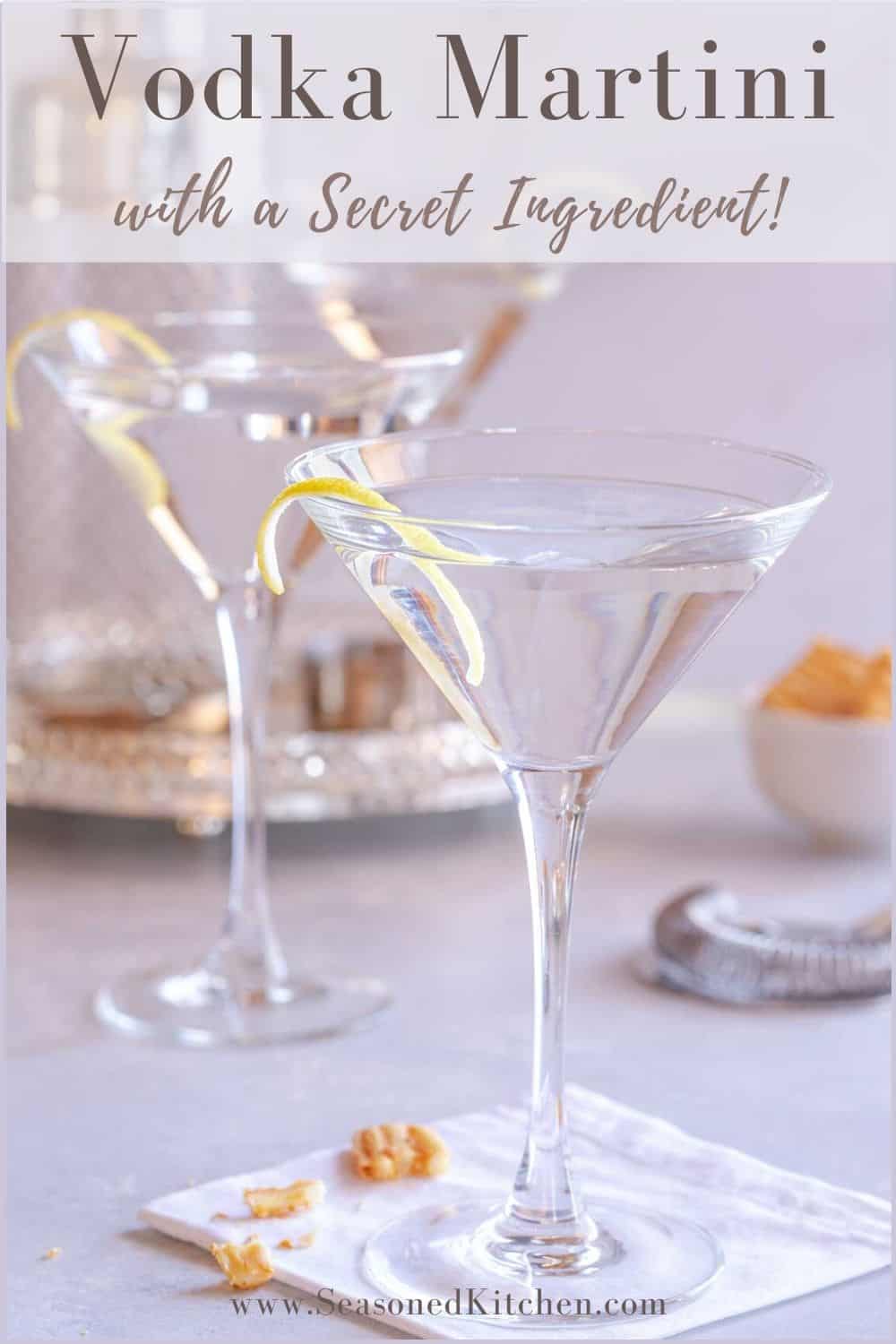 2 stemmed glasses holding vodka martinis with twists, with a shaker in the background