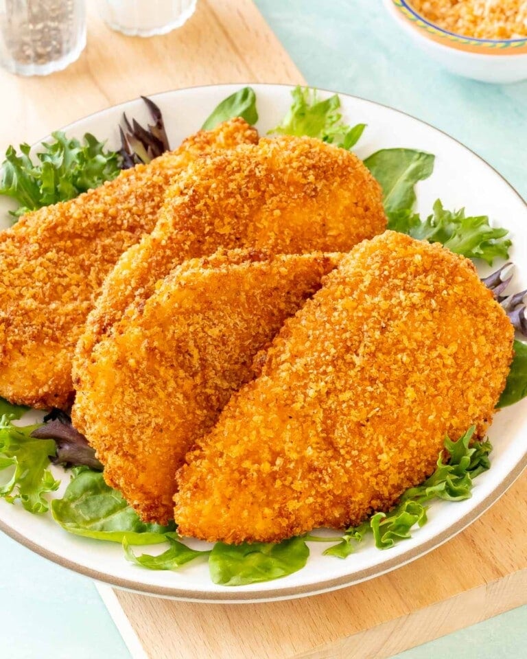 4 Air Fryer Fried Chicken Breasts on a plate, with fresh lettuce around the edges