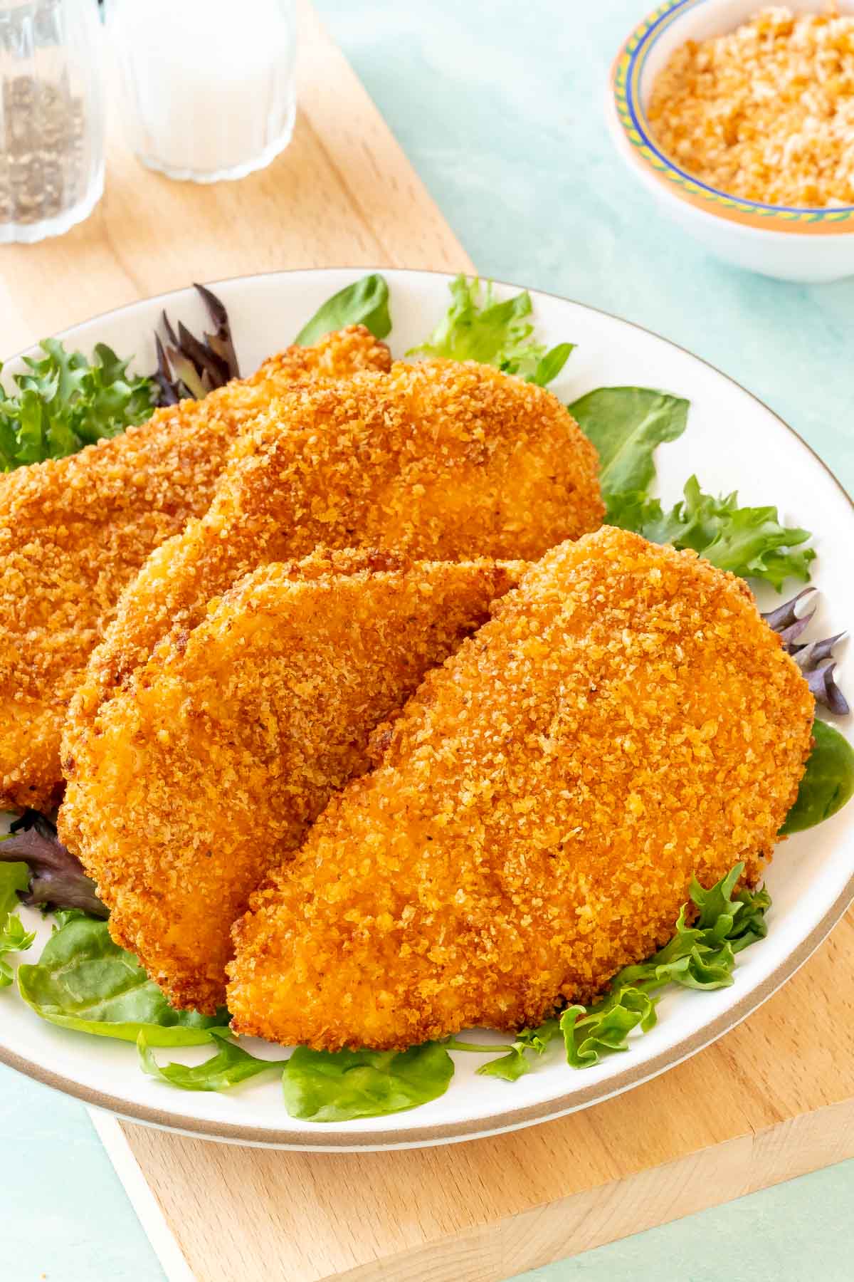 4 Air Fryer Fried Chicken Breasts on a plate, with fresh lettuce around the edges