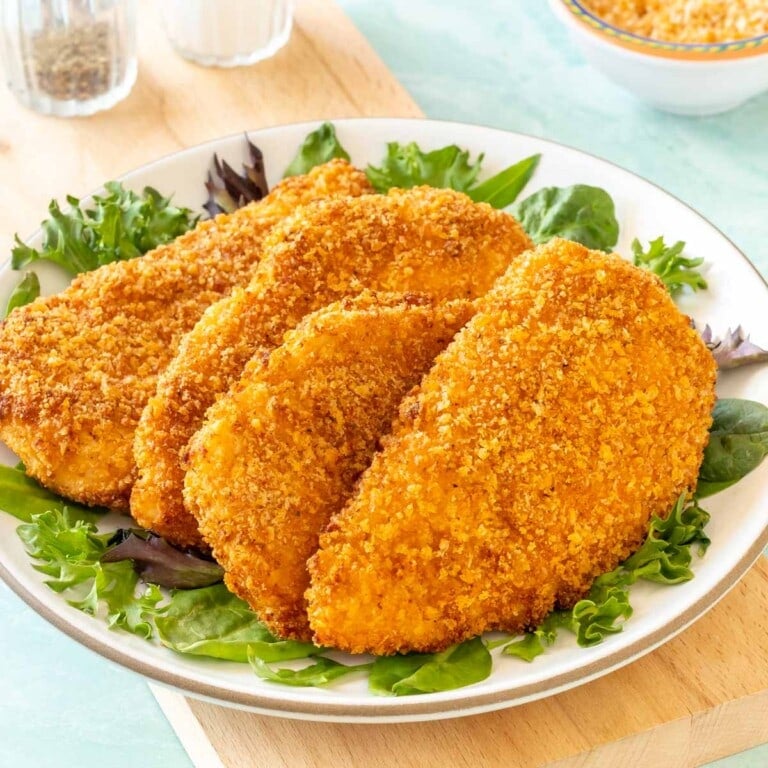 4 Air Fryer Fried Chicken Breasts on a plate, with fresh lettuce around the edges