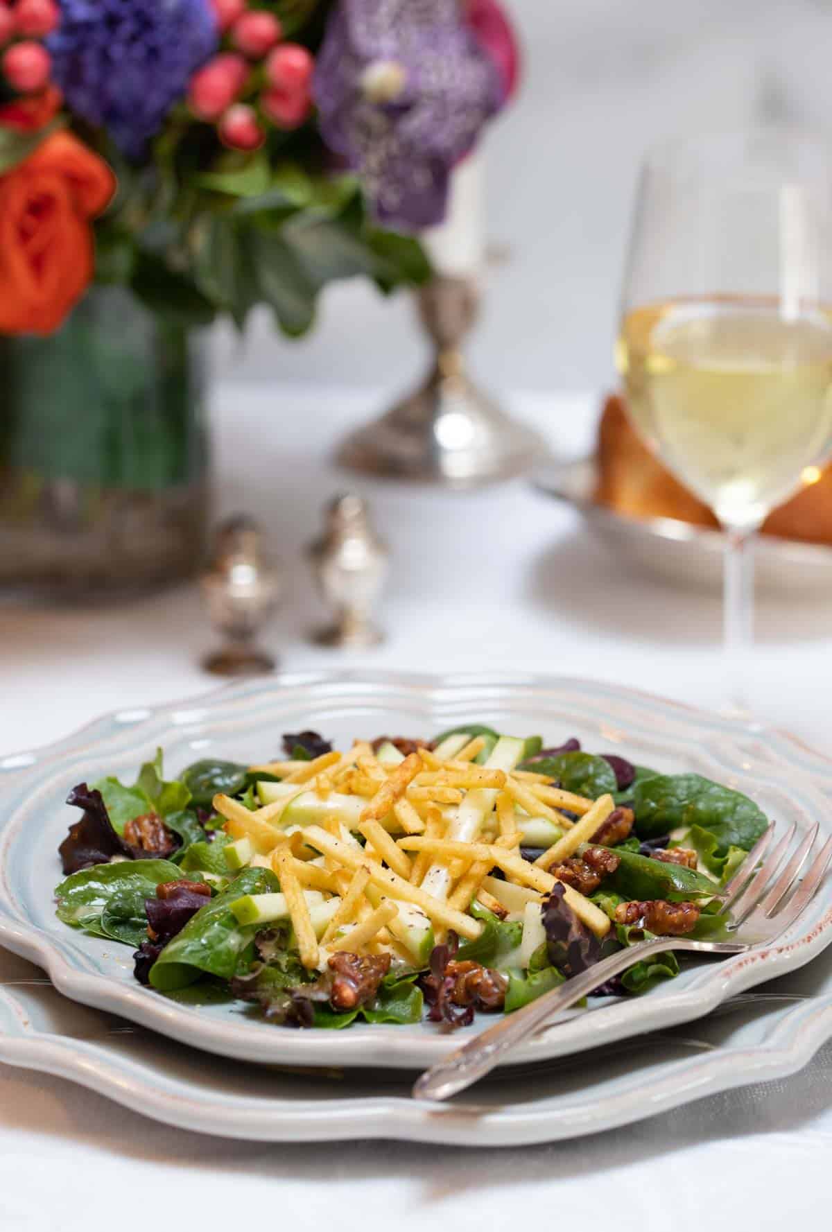 Individual plate filled with Apple and Mixed Green Salad with Apple-Truffle Vinaigrette