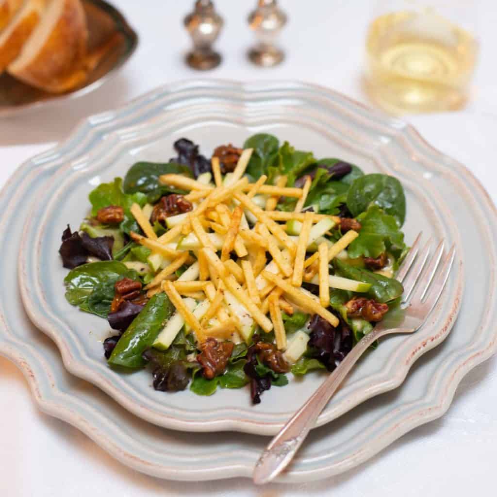 Individual plate filled with a serving of Apple and Mixed Greens Salad with Apple-Truffle Vinaigrette