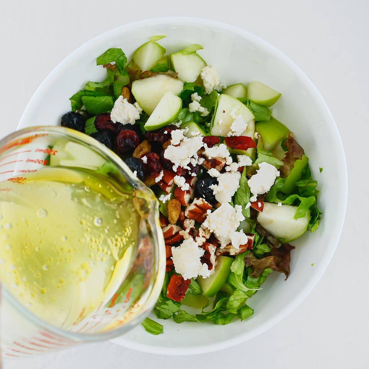 Pouring the dressing on the apple feta salad.