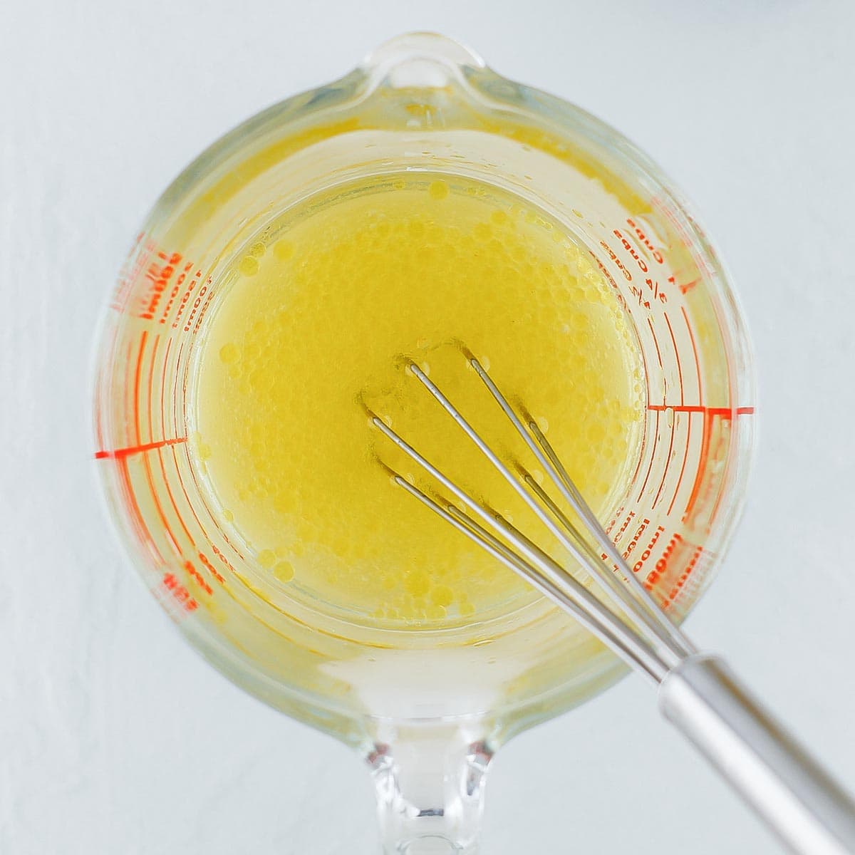 Apple feta salad dressing in a glass measuring cup with a whisk.