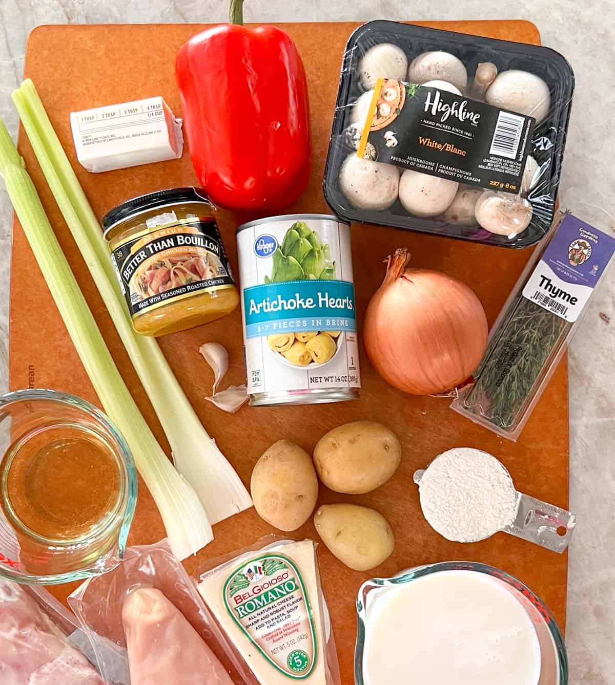 Ingredients for Creamy Artichoke Chicken Soup are arranged on a cutting board.