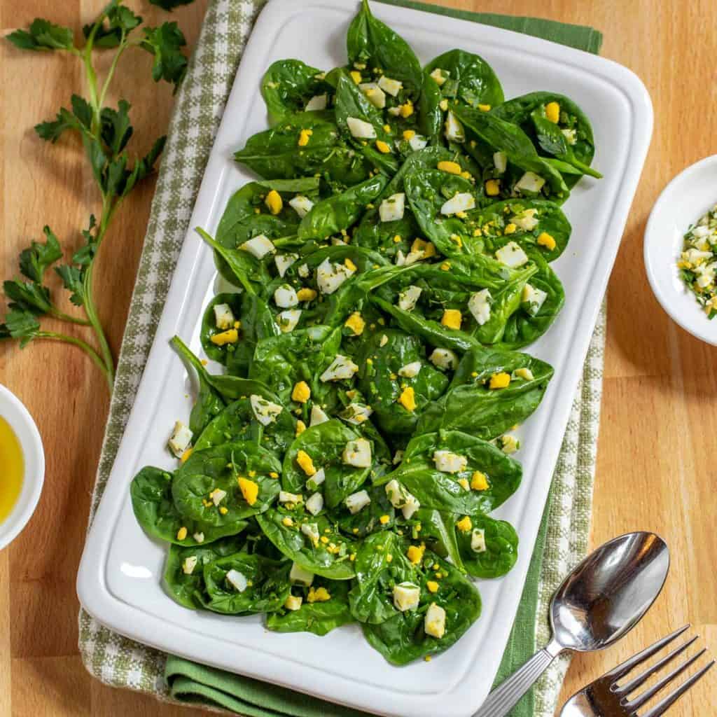 White square platter showing Baby Spinach Salad with Lemon Dijon Dressing