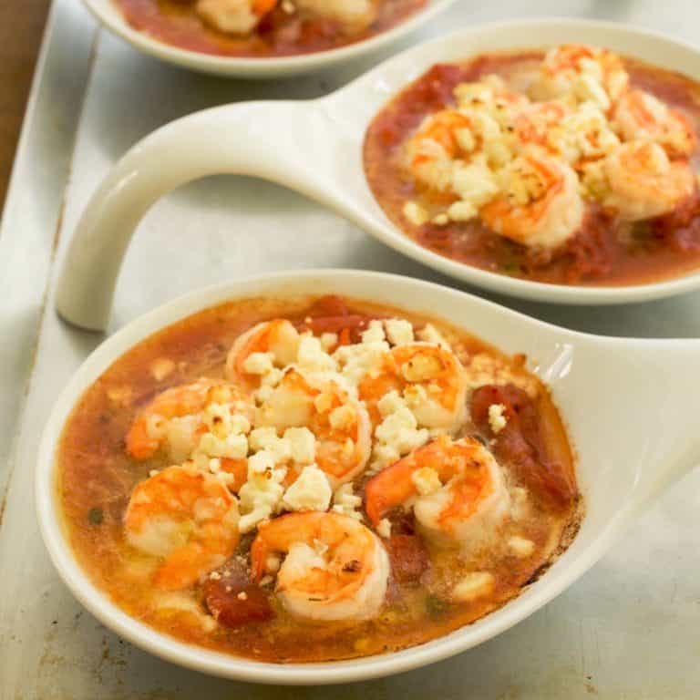 Individual white ramekins filled with Baked Shrimp with Tomatoes, Feta and Capers