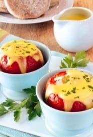 Light blue cups filled with Baked Eggs in Tomatoes with Easy Blender Hollandaise Sauce