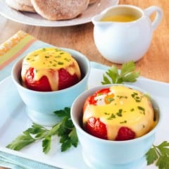 Light blue cups filled with Baked Eggs in Tomatoes with Easy Blender Hollandaise Sauce